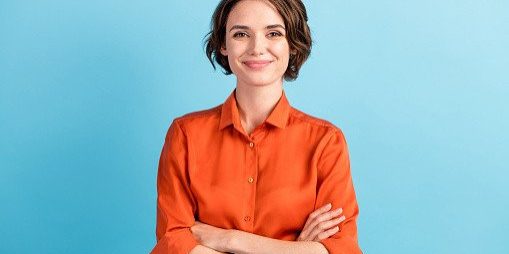 Photo of attractive charming lady cute bobbed hairdo arms crossed, self-confident person worker friendly smile good mood wear orange office shirt isolated blue color background